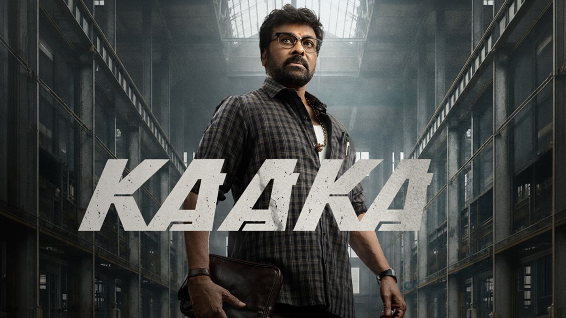 Man in glasses stands in a dark corridor behind the title “KAAKA.”